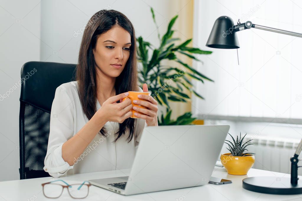 Young female business person working in office using laptop, rea