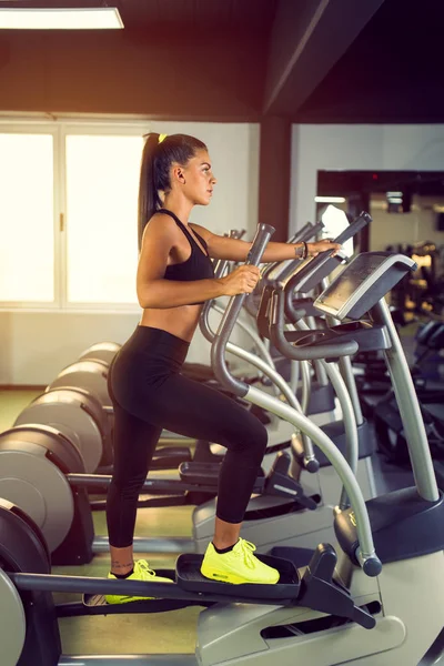 Profile of young smiling woman exercising in health club