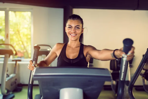 Profile of young smiling woman exercising in health club