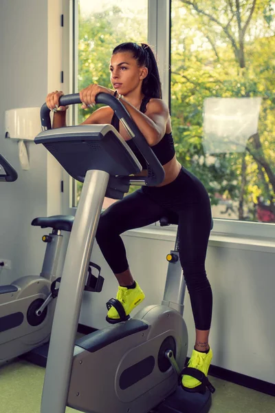 Woman Doing Cardio Exercises on a Stationary Bike at the Gym