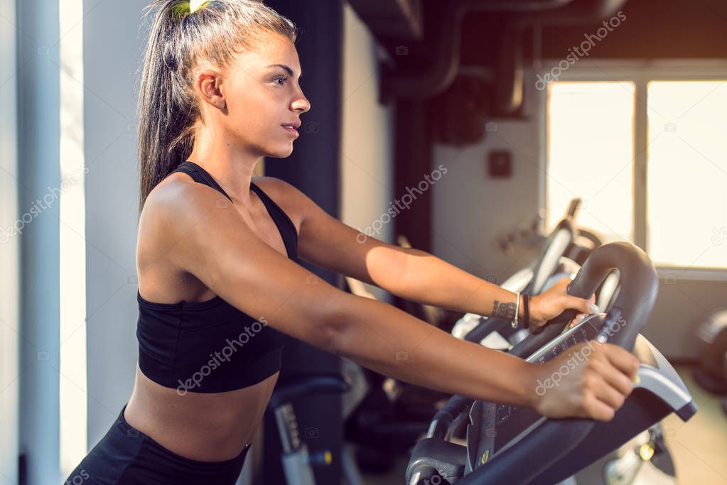 Woman Doing Cardio Exercises on a Stationary Bike at the Gym