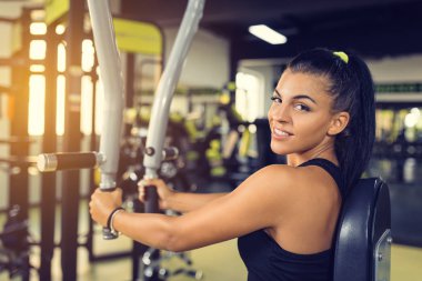 Genç kadın eğitim üst vücut sinek makine kullanarak