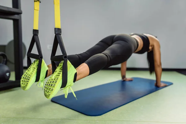 Fit girl doing plank exercise on trx for back spine and posture