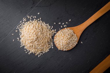 Beyaz Susam siyah granit backgroud kaşık içinde