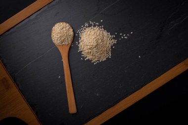 Beyaz Susam siyah granit backgroud kaşık içinde