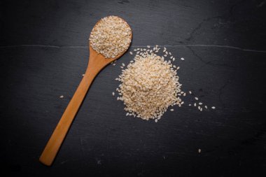 Beyaz Susam siyah granit backgroud kaşık içinde