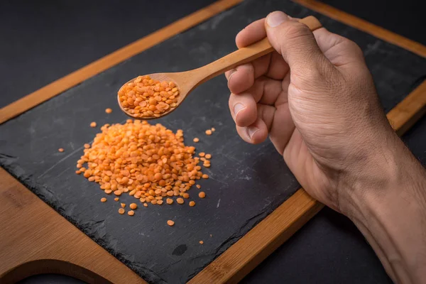 Mercimek siyah granit arka plan üstünde tahta kaşık tutan el