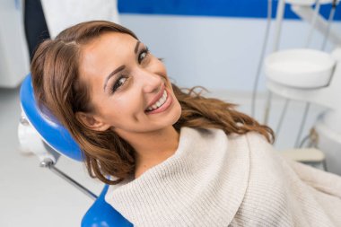 Diş kliniğinde gülümseyen kadın hasta