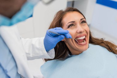 Genç kendine güvenen erkek dişçi klinikte kadın hastaya tıbbi tedavi. Diş Kliniği kavramı