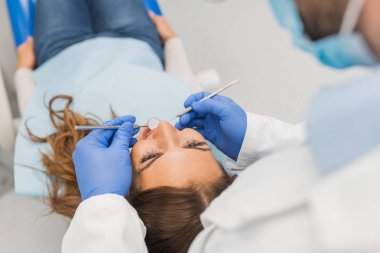 Diş hekimi diş ekipmanları ile inceleyerek kadının yüksek açılı görünüş 