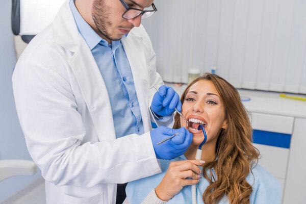 High angle view of dentist examining woman with dental equipments 