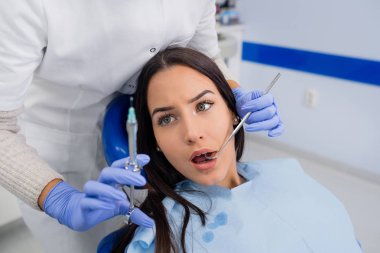 Girl shocked by a needle at the dentist office clipart