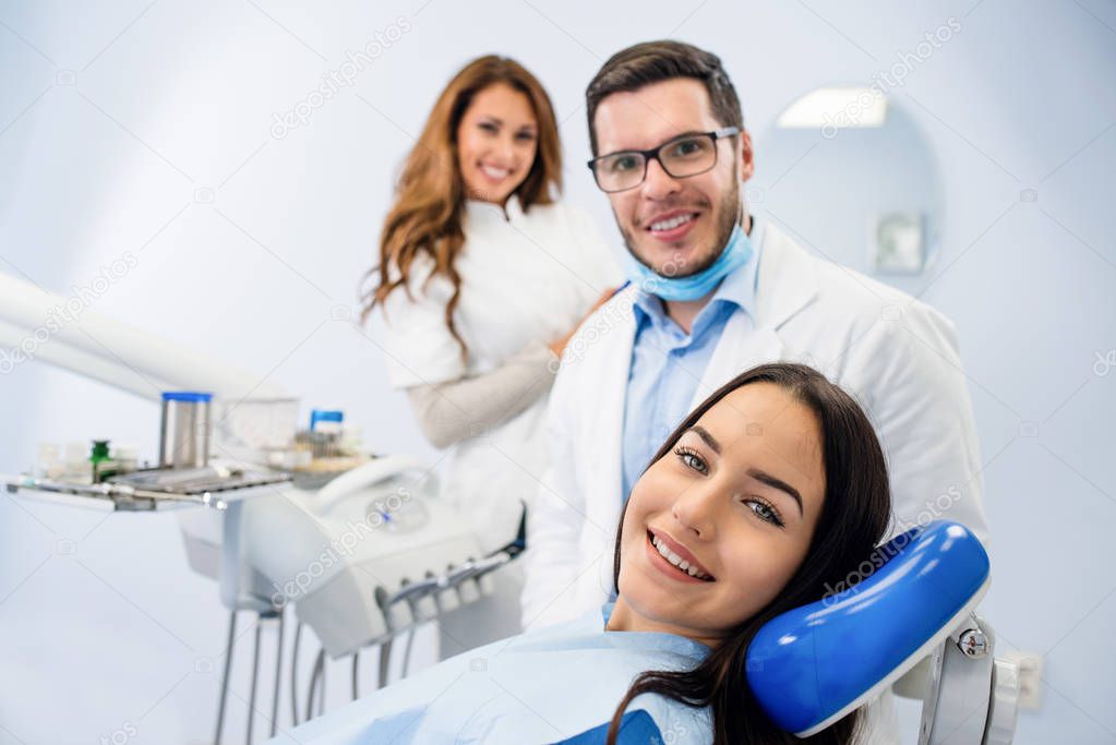 Young confident male dentist Medical treatment to a female patient at the clinic. Dental clinic concept