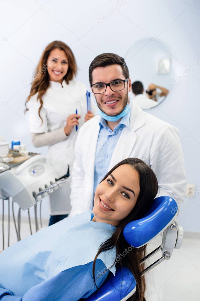 Young confident male dentist Medical treatment to a female patient at the clinic. Dental clinic concept