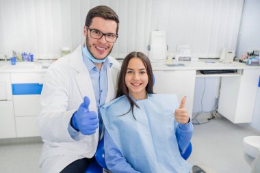 Diş hekimi doktor ve küçük kız kameraya gülümseyen. Yukarı başparmak