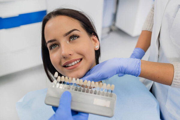 Стоматолог, изучающий белизну зубов пациентов
