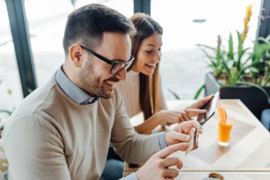 Randevularında kahve içen güzel bir çift online alışveriş için dijital tablet ve kredi kartı kullanıyor.