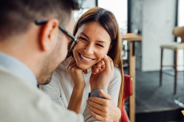 Birbirine bakarak kafede oturan genç sevmek çift.