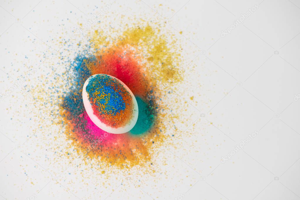 Multicolored pigments scatter over an egg. Art concept.