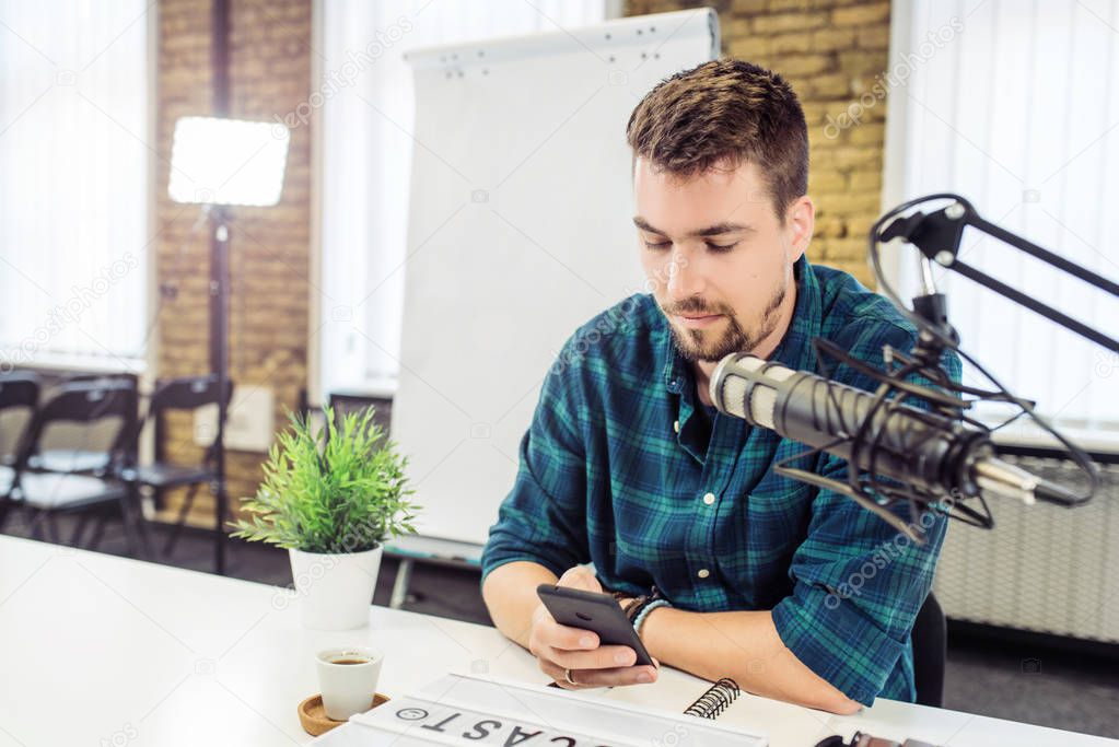 Young man reading funny comments from radio listeners during live talk show.