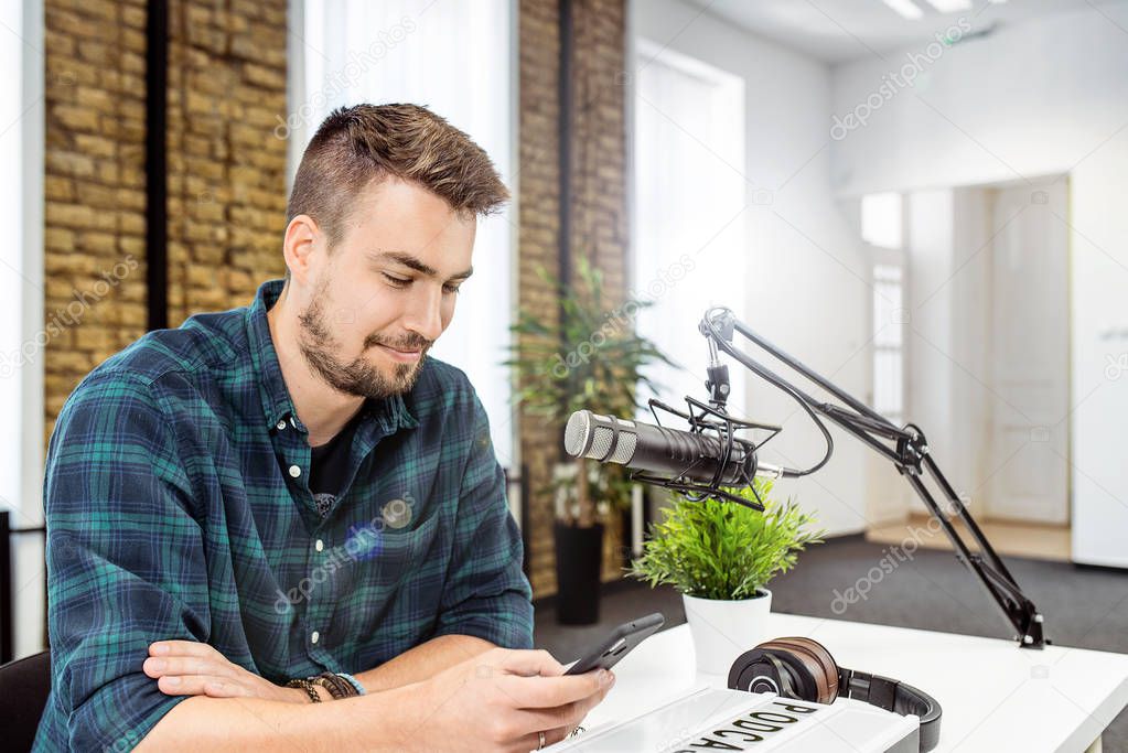 Young man reading funny comments from radio listeners during live talk show.