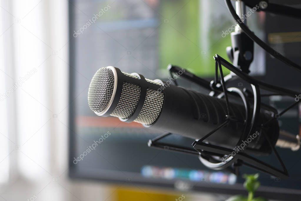 Microphone in the foreground. Blurred background. Software for recording and editing sounds. Post production.