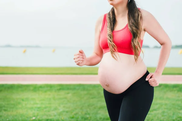 Pregnant woman walking in the park with a dumbbells in hands — Stock Photo, Image