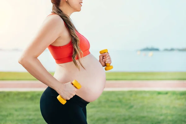 Femme enceinte faisant de l'exercice dans la nature . Image En Vente