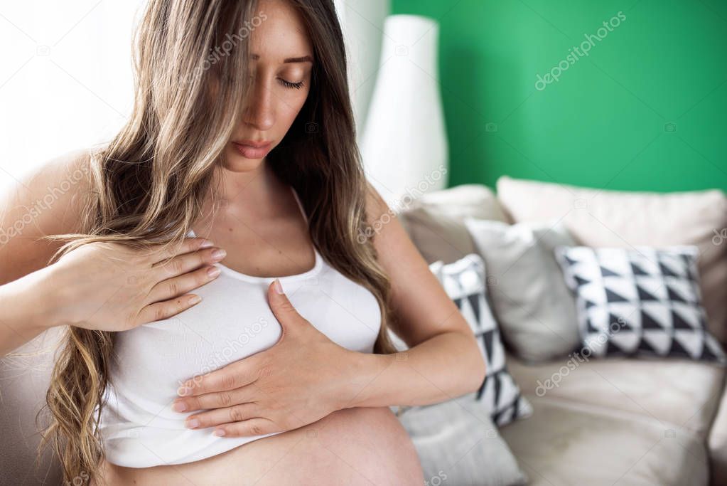 Closeup of pregnant woman having painful feelings in breast