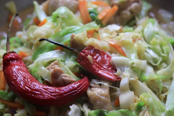 Two types of cabbage, fresh and ground, stewed with meat and hot red pepper. Lies on a beautiful plate. House food.