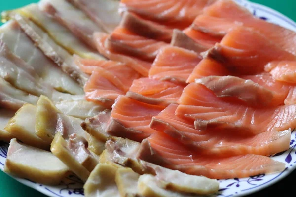 On a beautiful plate lies two types of smoked fish, sturgeon and salmon.