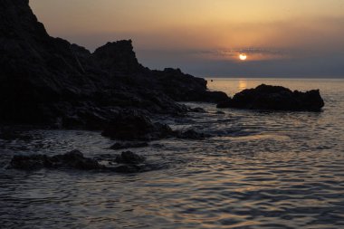 kayalar ile denizde turuncu gün batımı