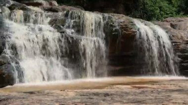 Orman şelalesi zemin taşındaki kayalardan hizaya geldi. Yerdeki kelebeklerle