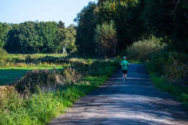 bir koşucu tarlalar ve merak ile güzel bir günde yürür