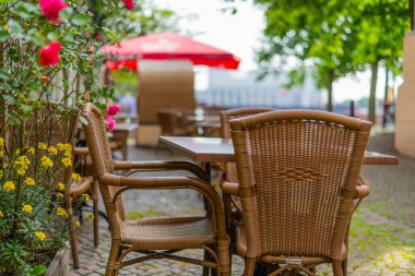 Yaya bir alanda, kahvenin önünde tahta sandalyeler ve masalar.