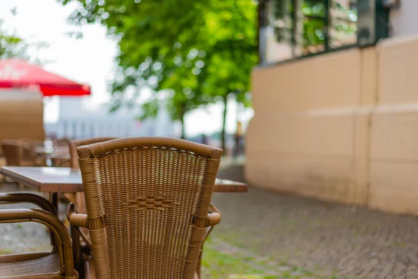 wooden  chairs and tables in a pedestrian area in front of a coffee