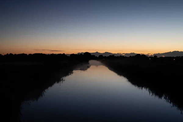 a river glows at night  with the horizon along with dark landscape