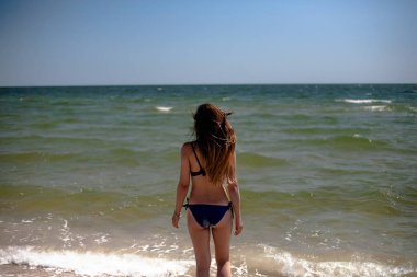 Deniz sahilinde mayo giymiş genç bir kız..