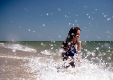 Deniz sahilinde mayo giymiş genç bir kız..