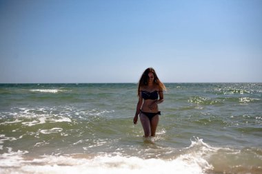 Deniz sahilinde mayo giymiş genç bir kız..