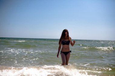 Deniz sahilinde mayo giymiş genç bir kız..