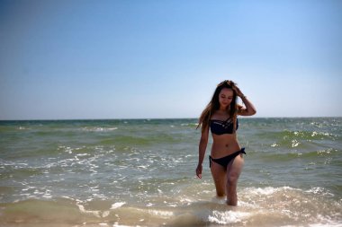 Deniz sahilinde mayo giymiş genç bir kız..