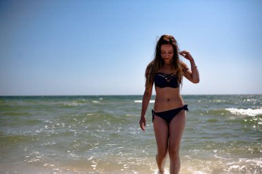 Deniz sahilinde mayo giymiş genç bir kız..