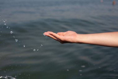 Denizin arka planında kız eli. Denizde tatil.