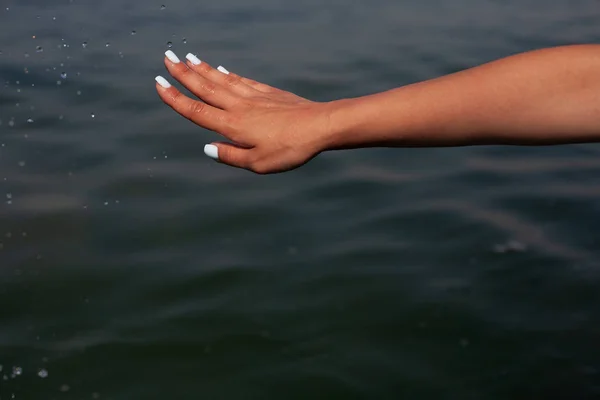 Girl\'s hand on a background of the sea. Holidays at sea.