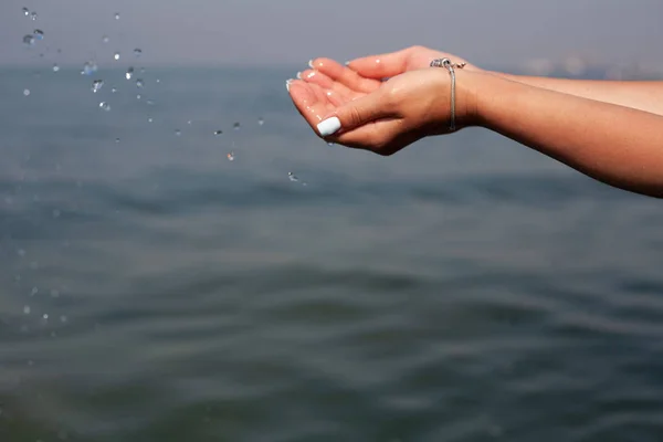 Girl\'s hand on a background of the sea. Holidays at sea.
