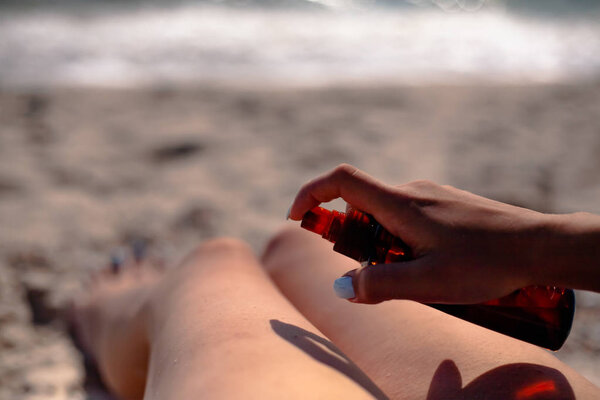 Girl smears sunblock. On the beach uses tanning oil.