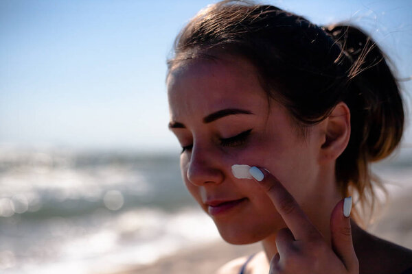 Girl smears sunblock. On the beach uses tanning oil.