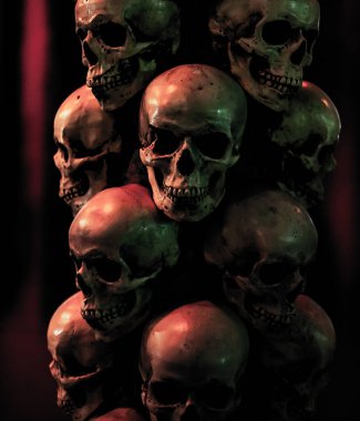 Karanlık bir arka plan üzerinde kasvetli kafatasları. Kafatasları üst üste durur.