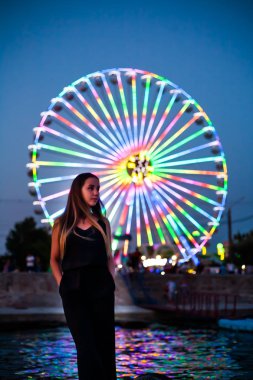 Geceleri dönme dolabın arka planında mutlu bir kız. Gece ışıkları dönme dolap.